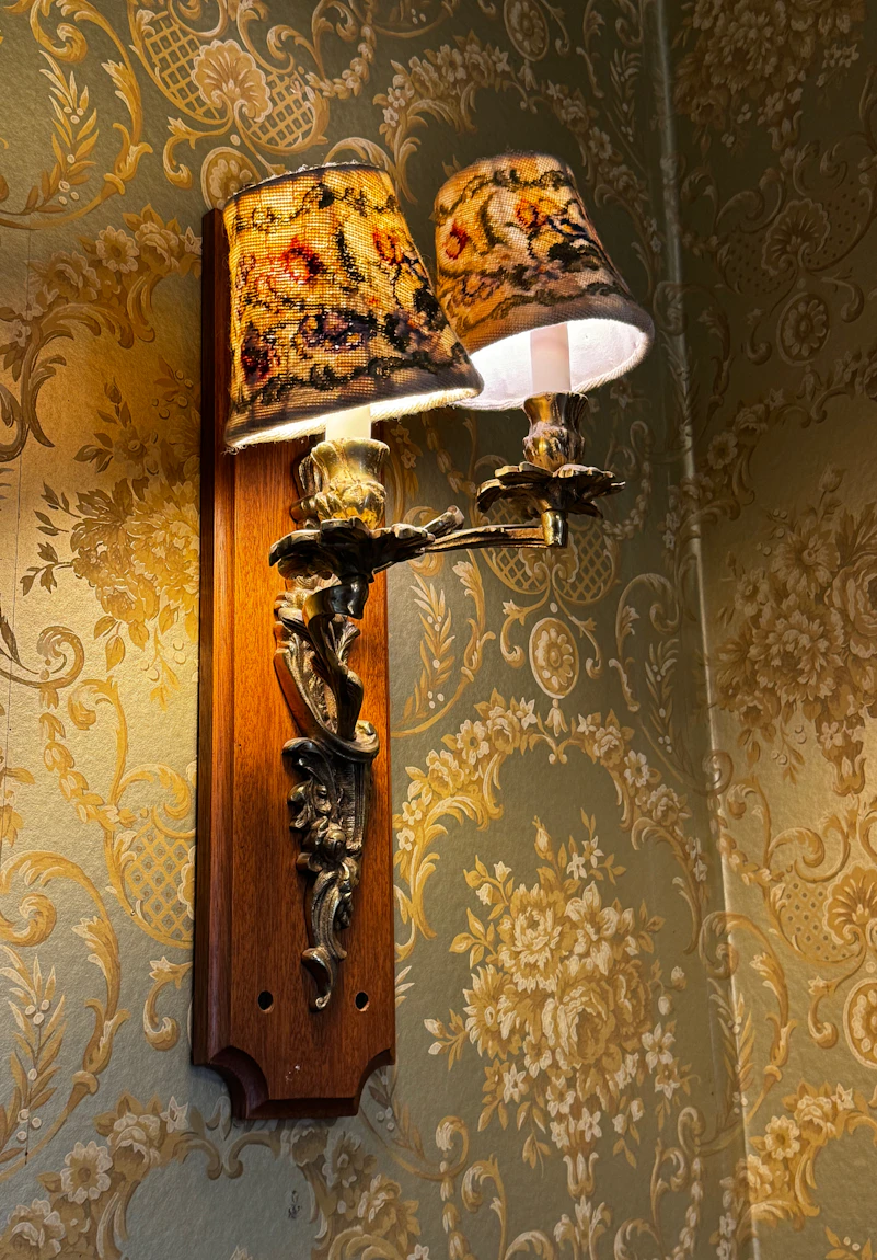 A brass wall lamp on the papered wall