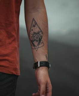 A pocket watch and hibiscus running down a forearm.