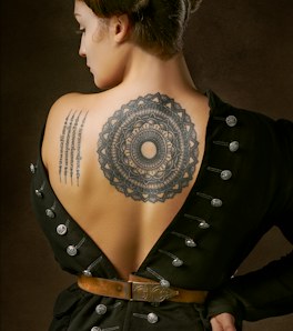 A snake coiled around a dagger down a spine, in fine line.