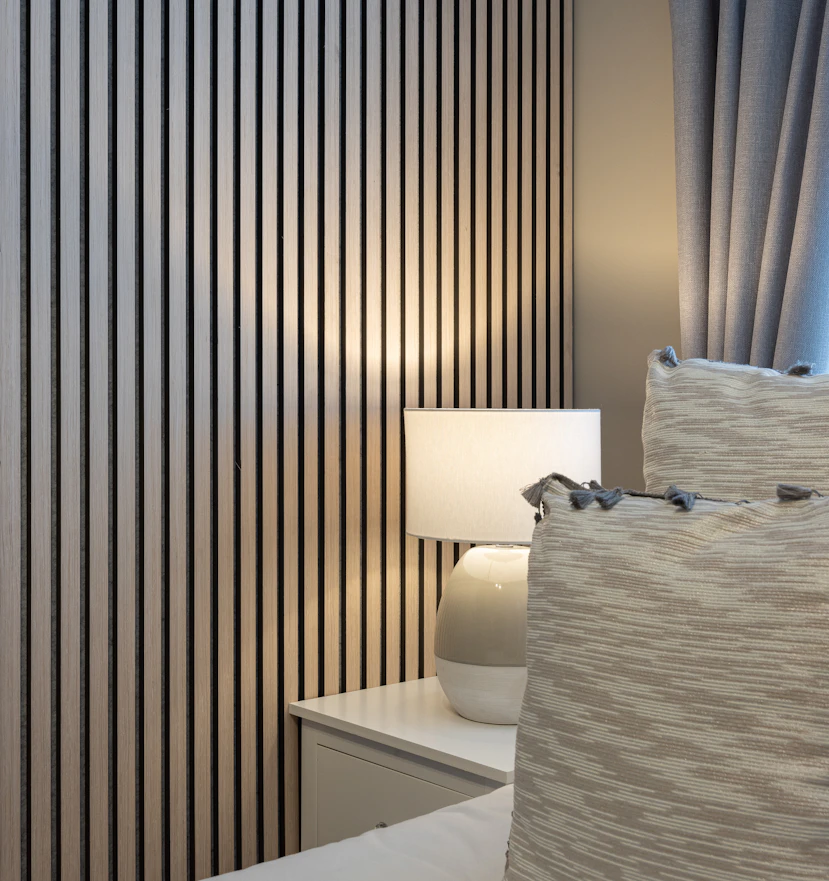 A full-height dark slatted feature wall beside a bedside lamp.