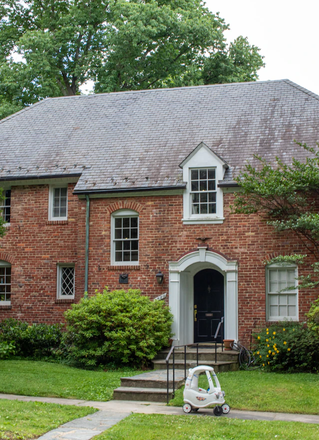 A brick house with the front door and window trim painted black.