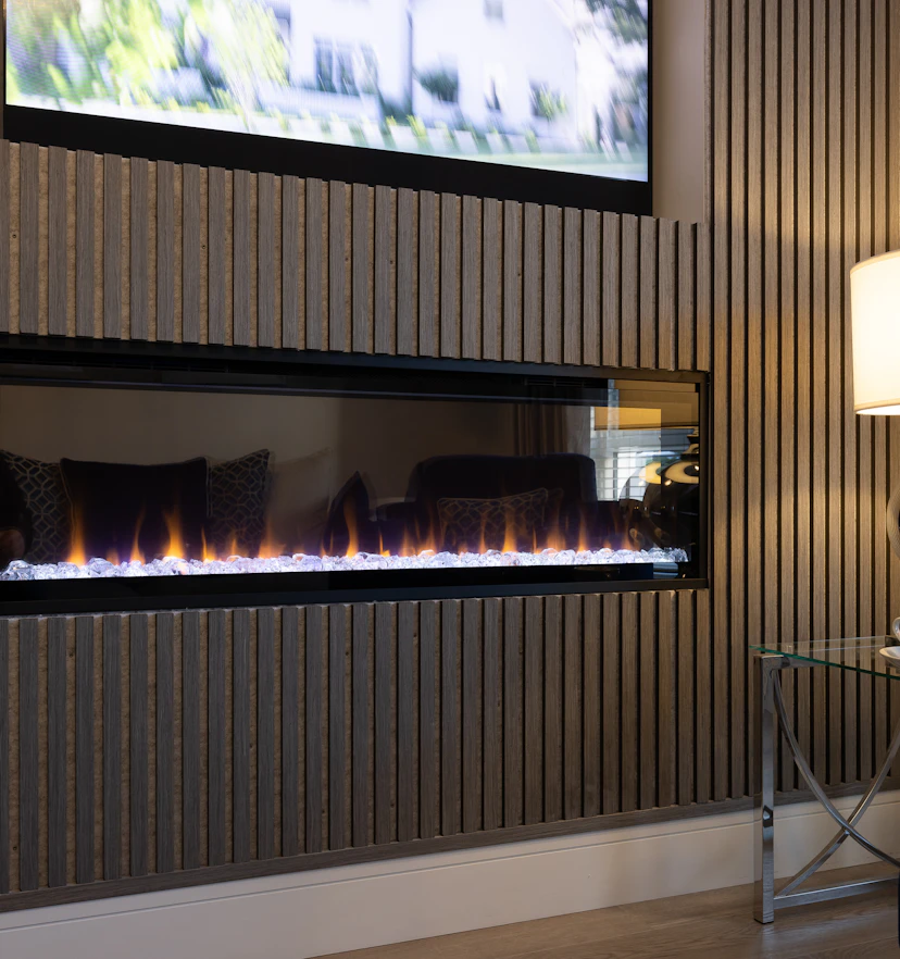 A dark slatted fireplace wall, freshly finished around the insert.