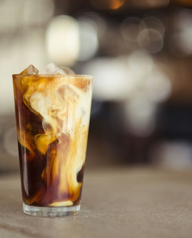 An iced latte in a tall glass, the milk still swirling into the coffee