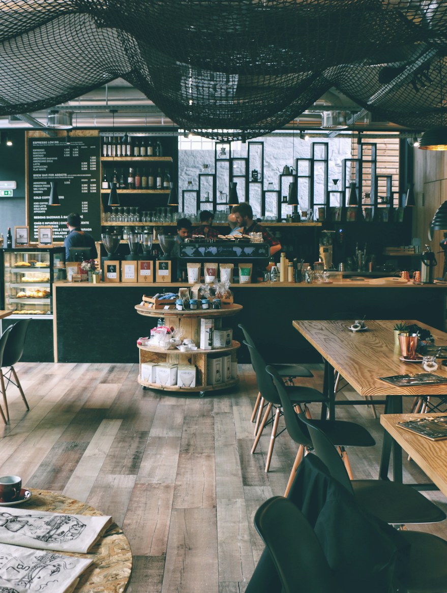 The long room: wooden tables and benches down one side, a chalkboard over the counter, and the shelves stacked with jars and beans