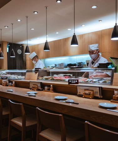The sushi counter inside Umeko, with pendant lights over a long white bar.