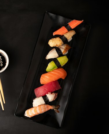 A long wooden board of nigiri, sashimi and rolls.