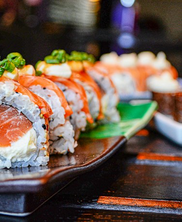 A slate board of rolls with lemon, pickled ginger and wasabi.
