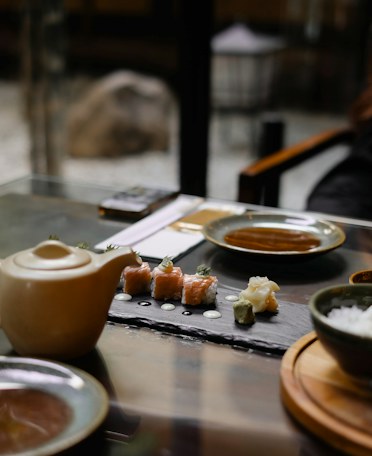 Two slate boards of sushi on a table, with soy sauce and chopsticks.