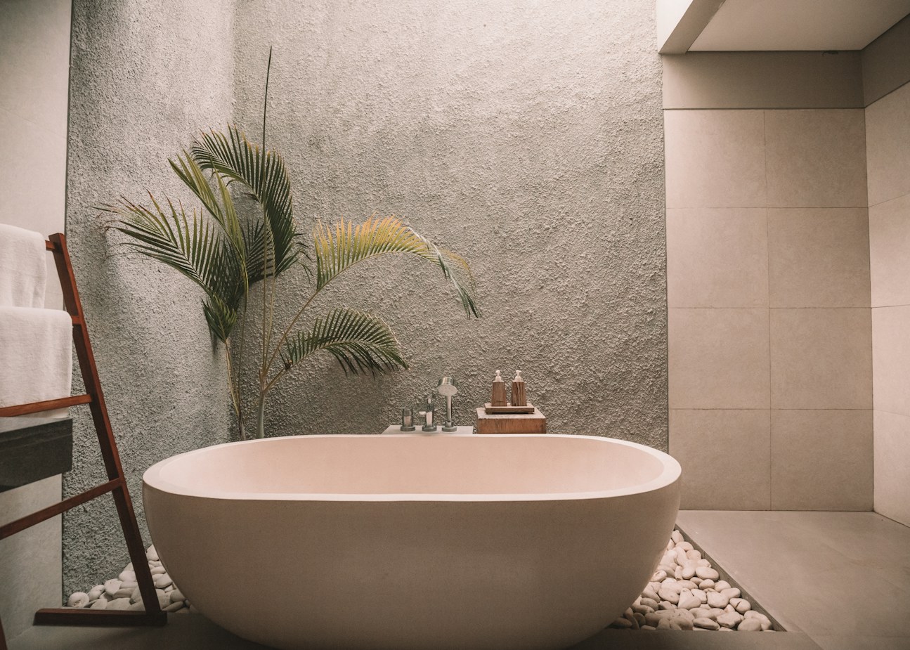 Bathroom with a warm stone tub, textured plaster walls and a pebble border