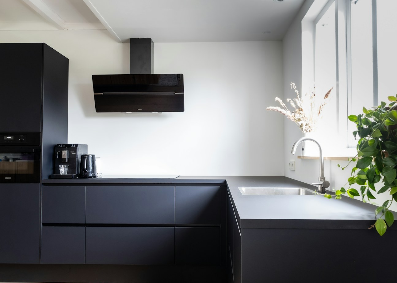 Completed condo kitchen with matte black cabinetry, quartz counters and integrated under-cabinet lighting