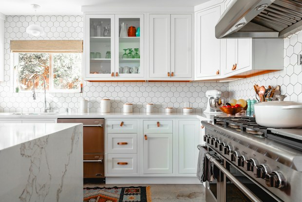 White kitchen with a waterfall marble island end and a pro-style range beyond